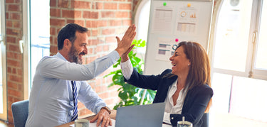 two people in business setting giving high fives and smiling | Lèlior Careers